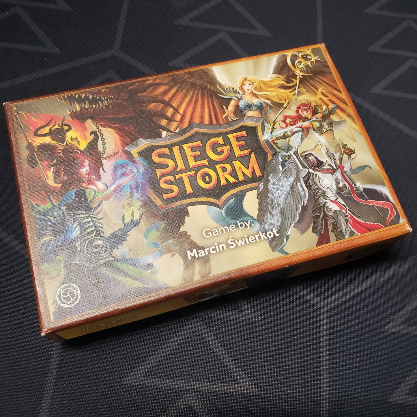 Image shows the front cover of the box for the Siege Storm card game