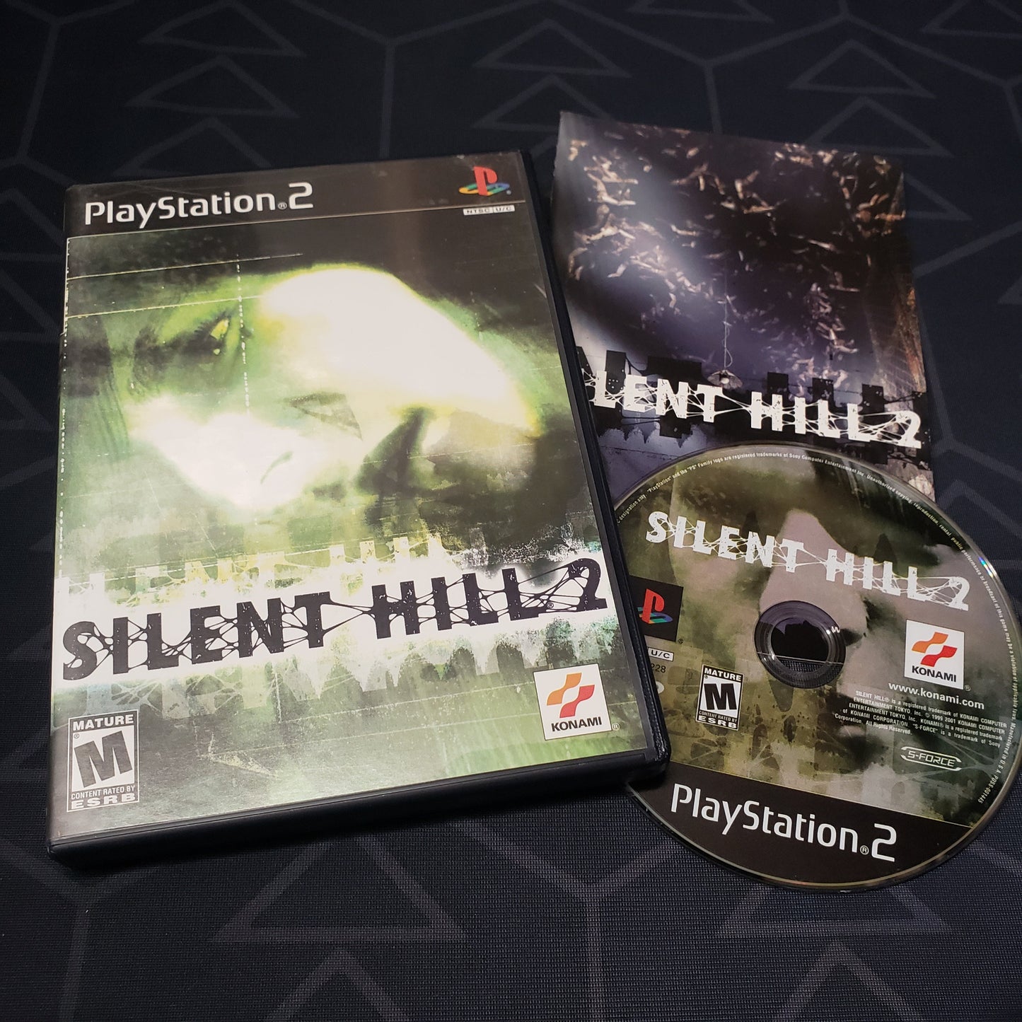 Image shows the case, manual and disc for the video game Silent Hill 2 for Playstation 2