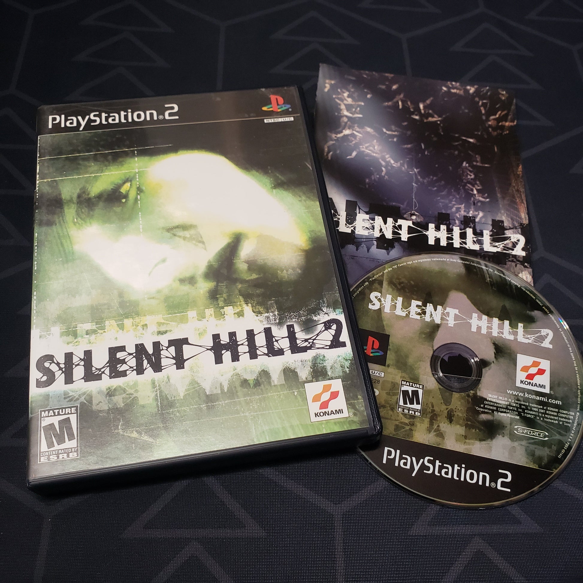 Image shows the case, manual and disc for the video game Silent Hill 2 for Playstation 2