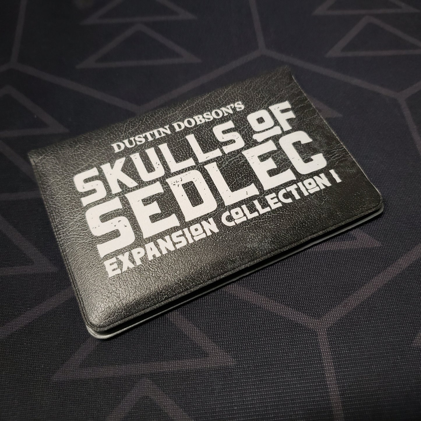 Image shows the front of the card wallet for the Expansion Collection I pack for the card game Skulls of Sedlec