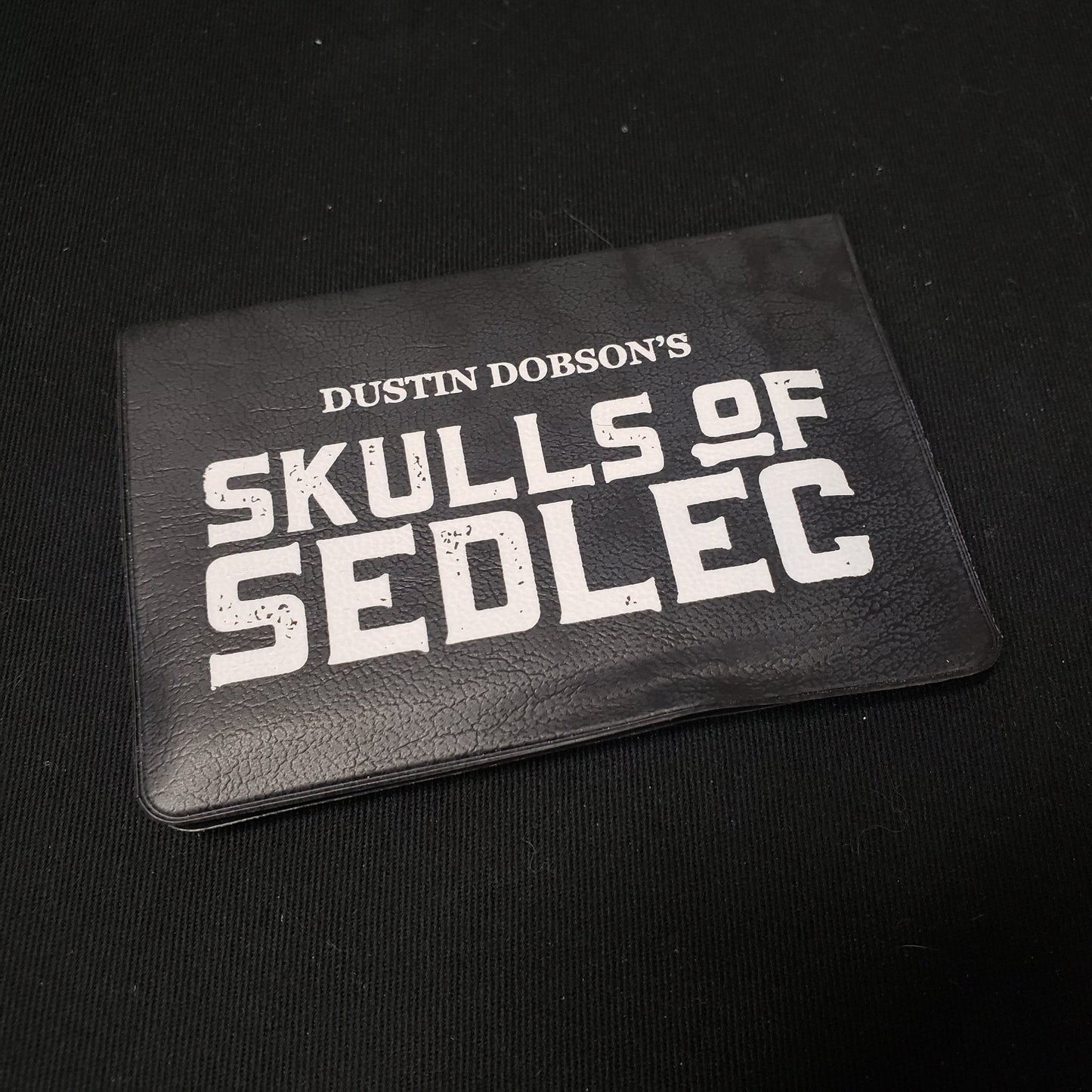 Image shows the front cover of the card wallet of the Skulls of Sedlec card game