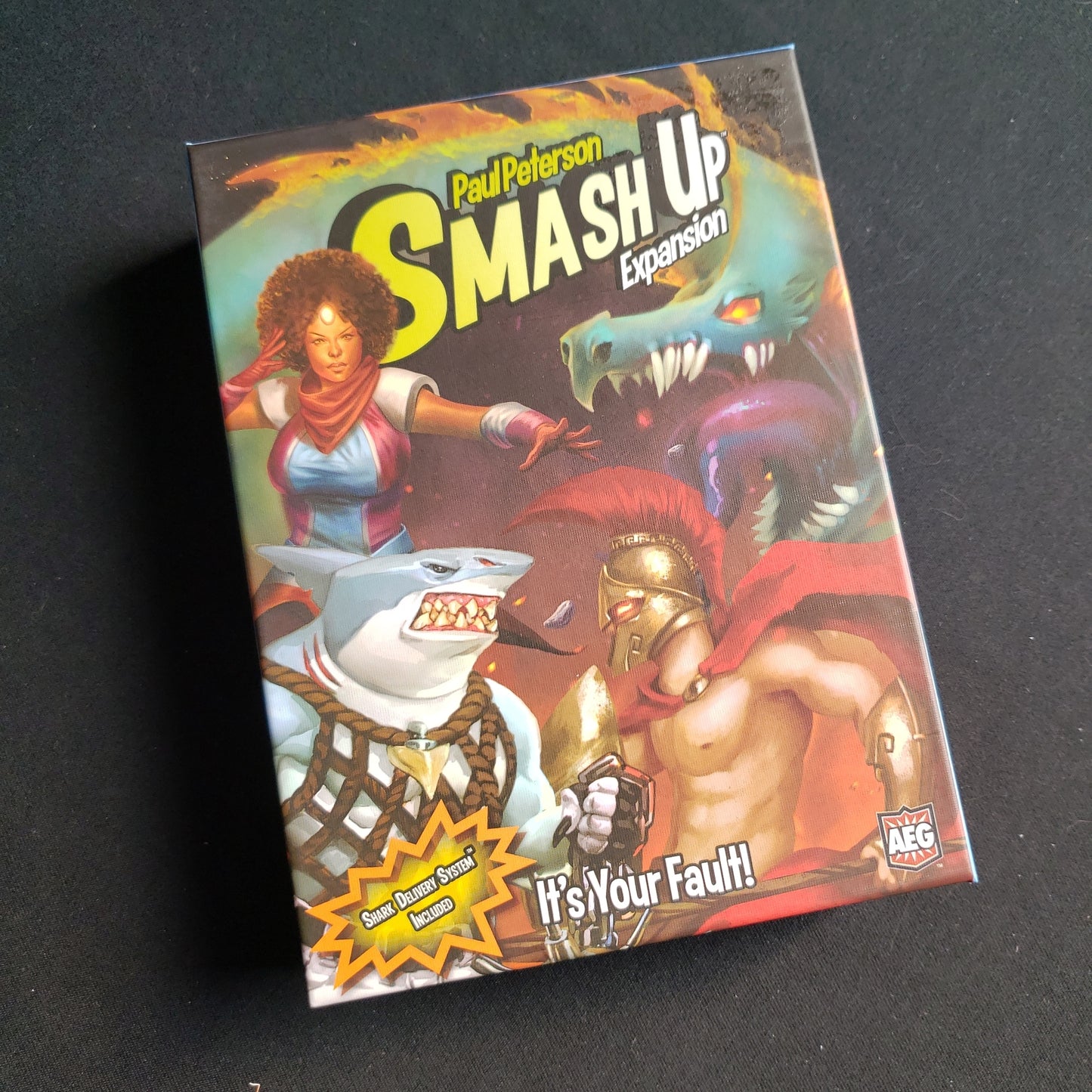 Image shows the front of the box for the It's Your Fault! Expansion for the Smash Up card game