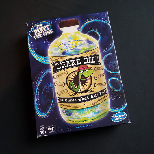 Image shows the front cover of the box of the Snake Oil card game
