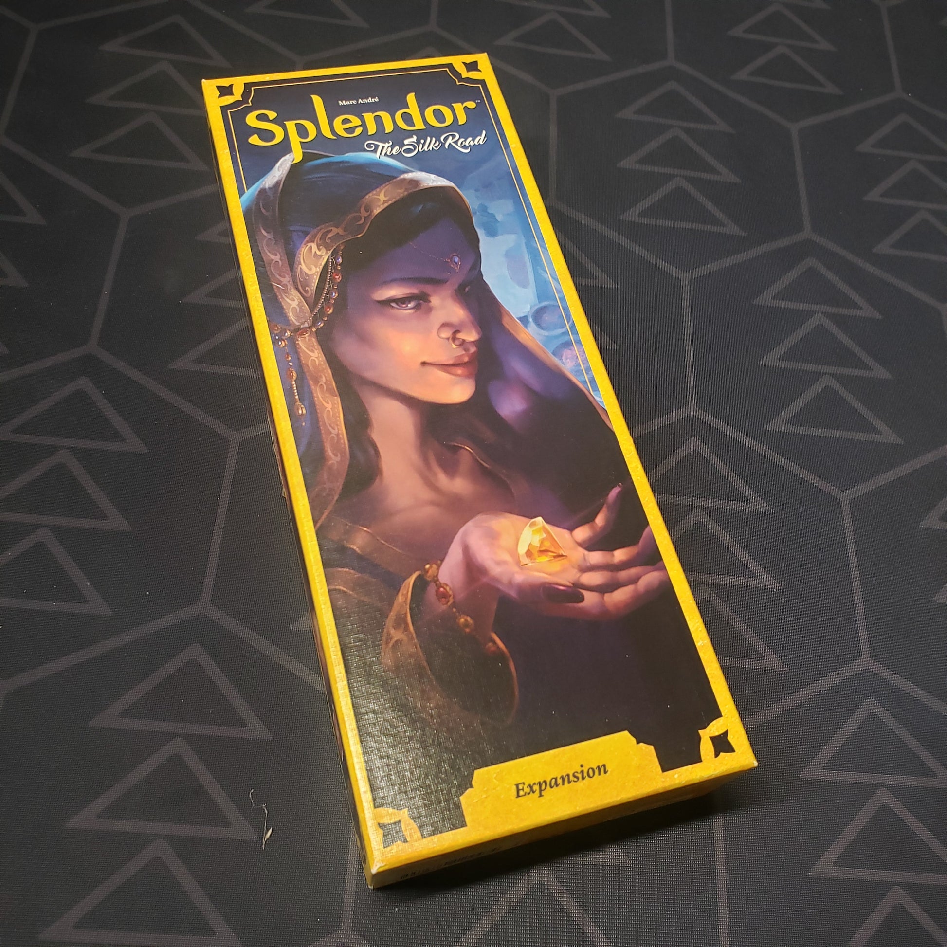 Image shows the front cover of the box of the Silk Road expansion for the board game Splendor