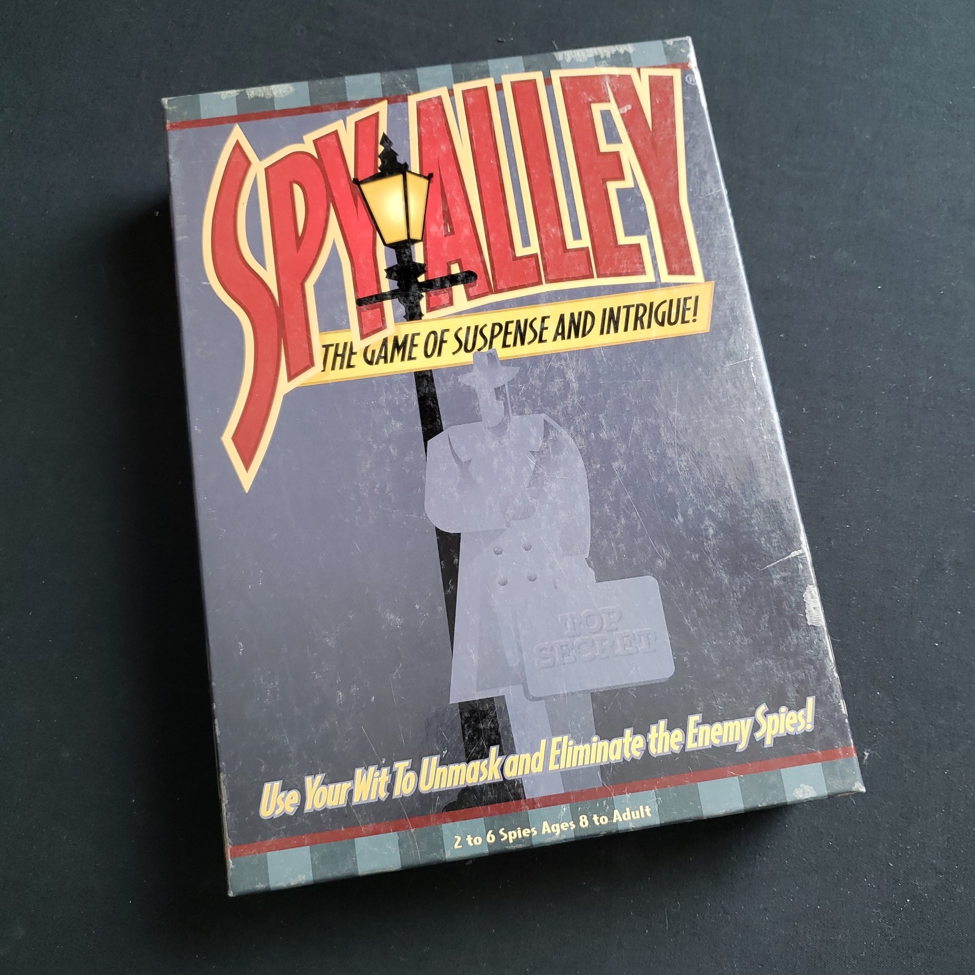 Image shows the front cover of the box of the Spy Alley board game