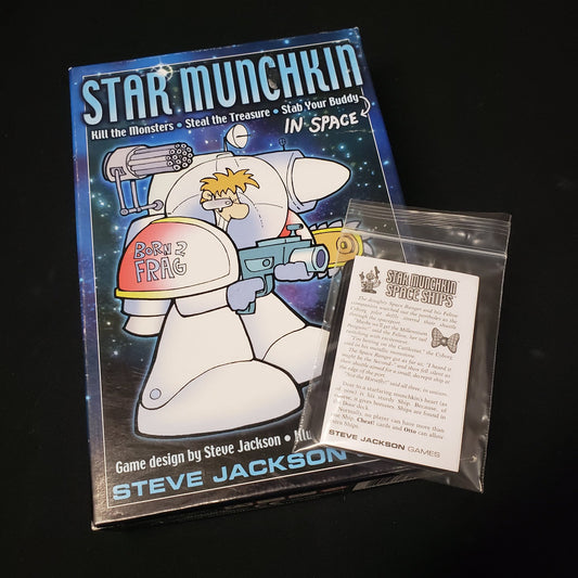 Image shows the front cover of the box of the Star Munchkin card game with a bagged expansion pack sitting on top of it