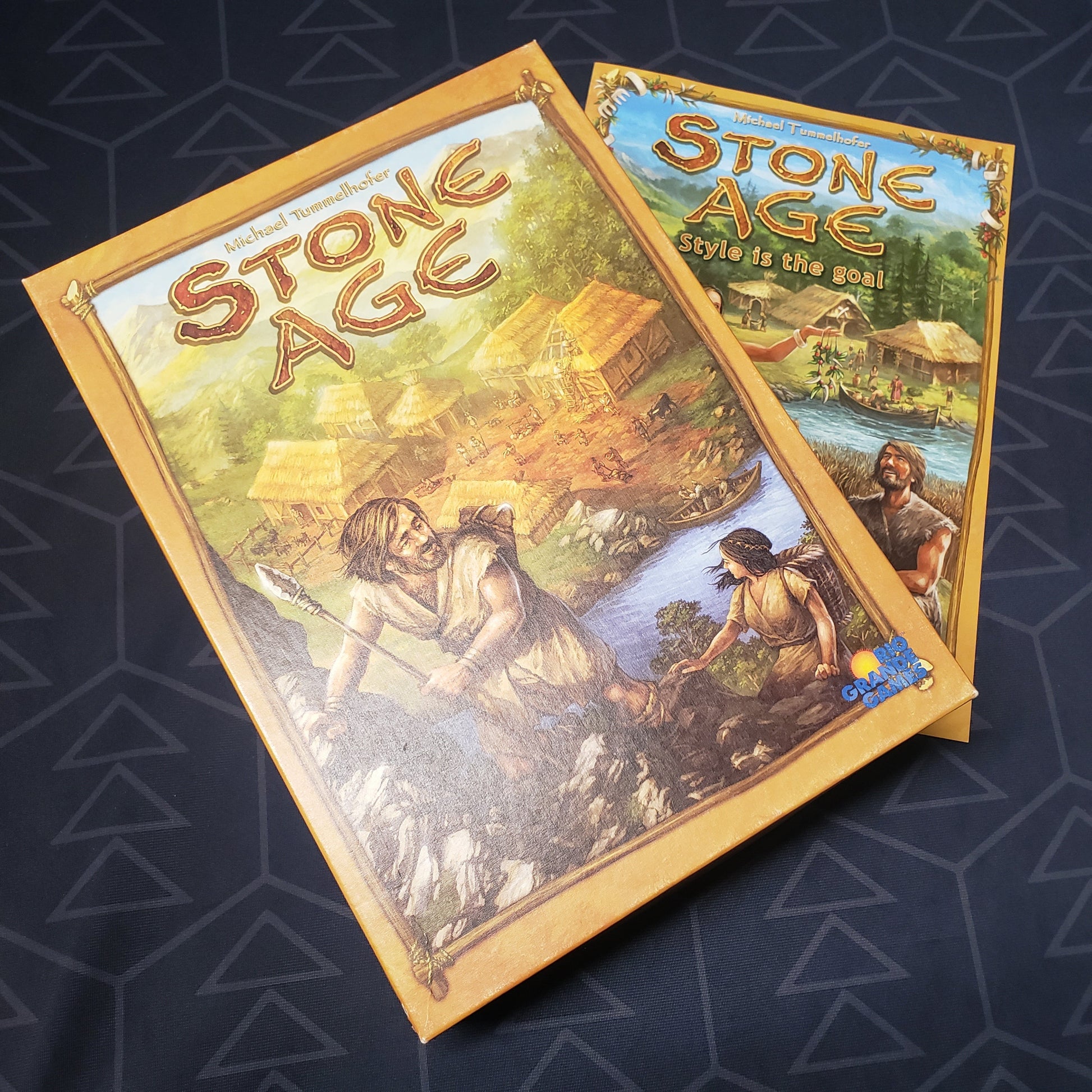 Image shows the front cover of the box of the Stone Age board game sitting on top of the instructions for the expansion