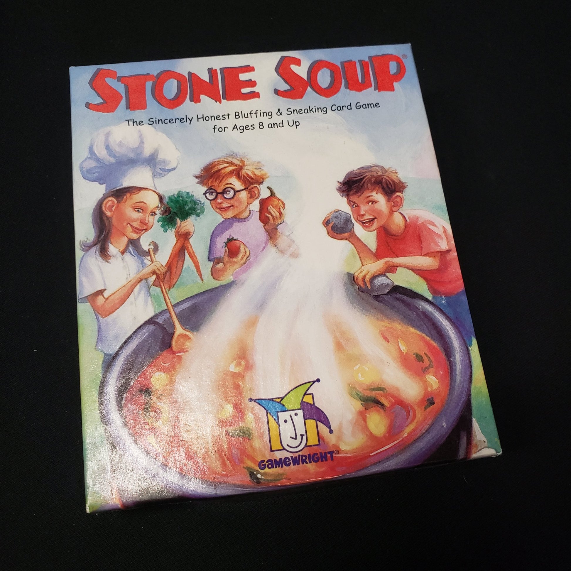 Image shows the front cover of the box of the Stone Soup card game