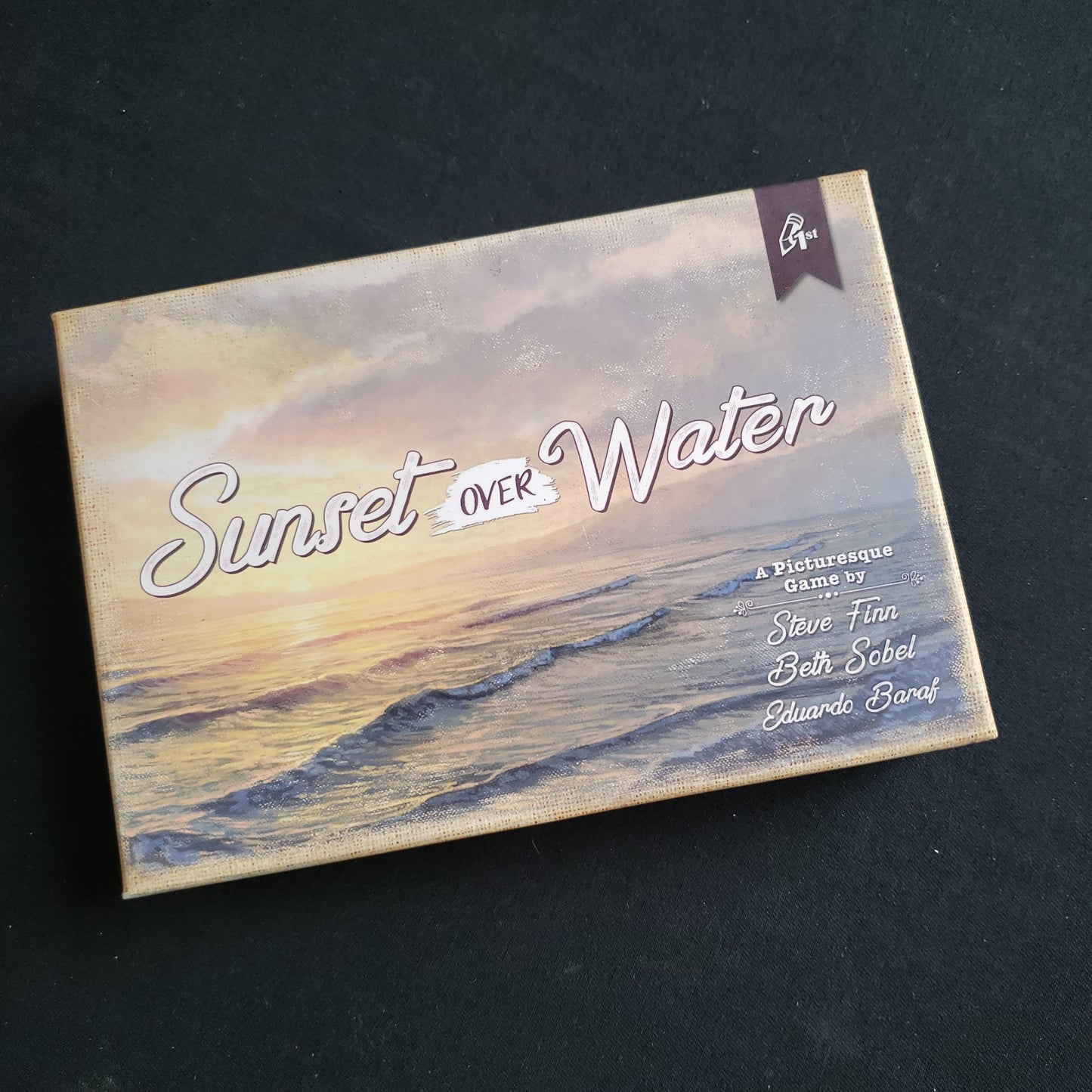 Image shows the front cover of the box of the Sunset Over Water card game