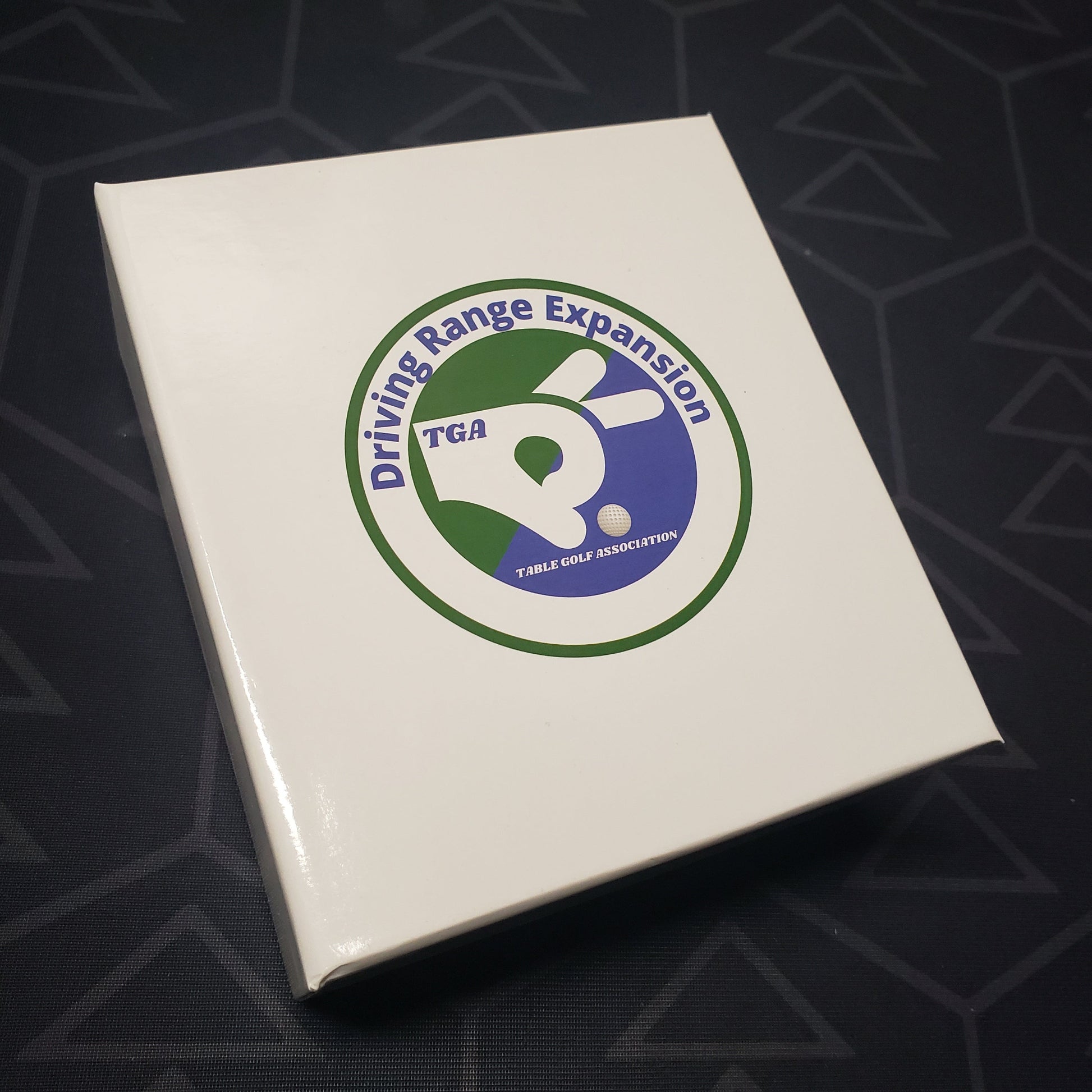 Image shows the front cover of the box of the Driving Range expansion for the board game Table Golf Association