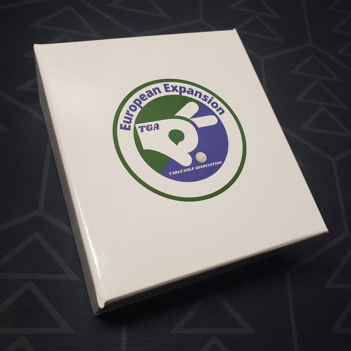Image shows the front cover of the box of the European expansion for the board game Table Golf Association