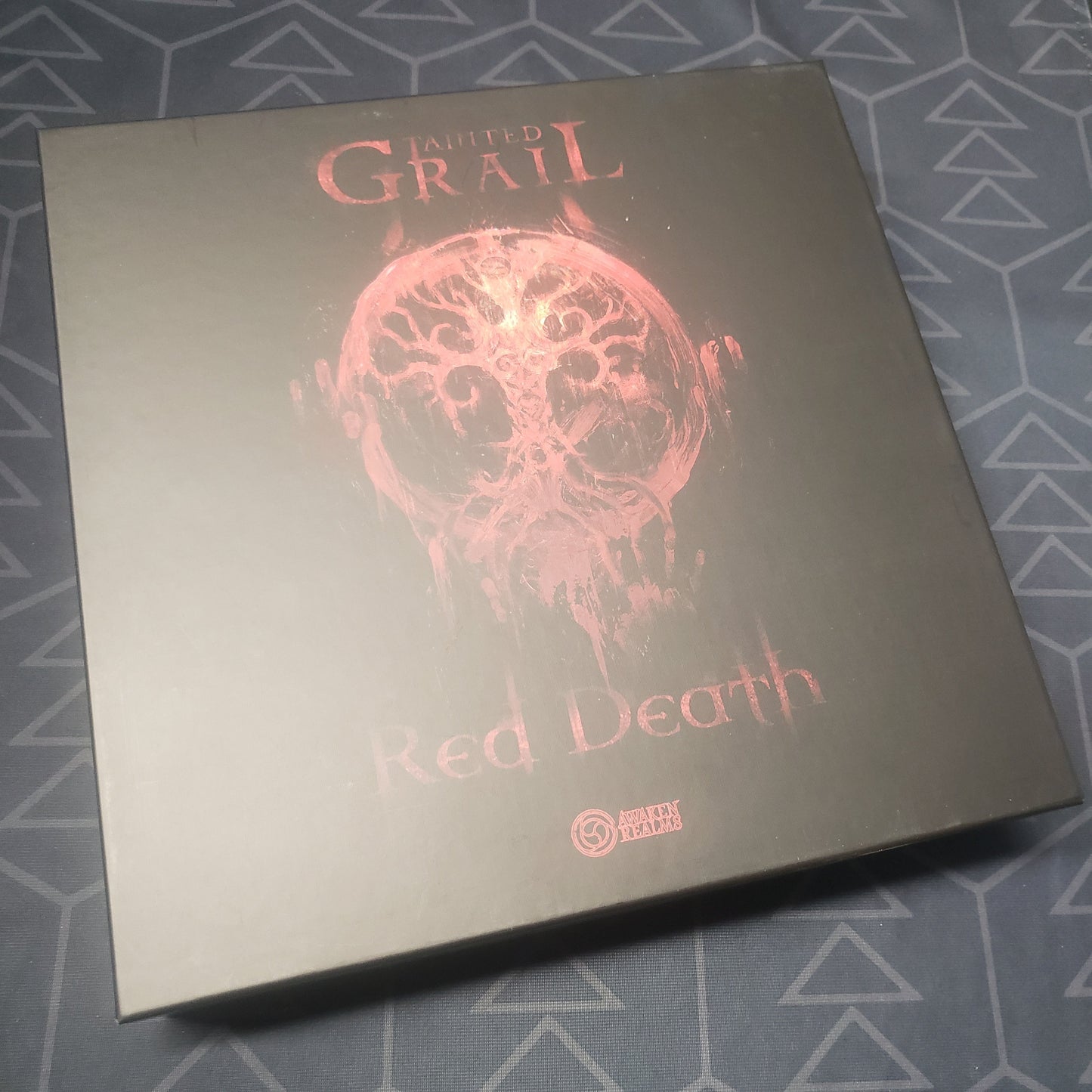 Image shows the front cover of the box of the Red Death expansion for the board game Tainted Grail