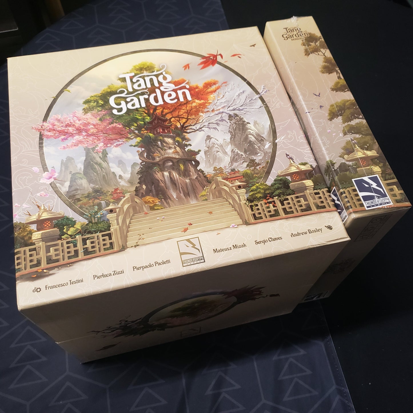 Image shows the top of the Big Box edition for the bpard game Tang Garden, with the sealed Seasons expansion box sitting next to it