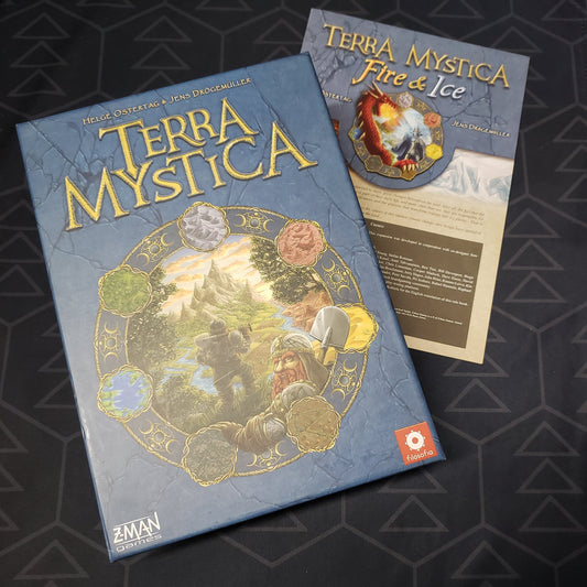 Image shows the front cover of the box of the Terra Mystica board game sitting on top of the instructions for the Fire & Ice expansion.