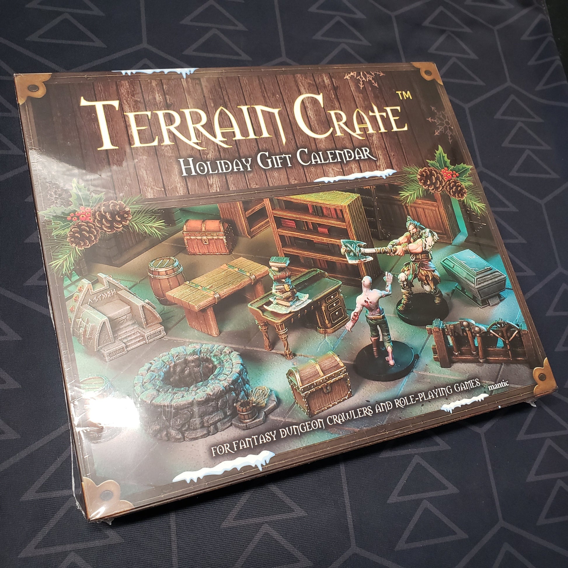 Image shows the front cover of the box for the Terrain Crate: Holiday gaming Gift Calendar