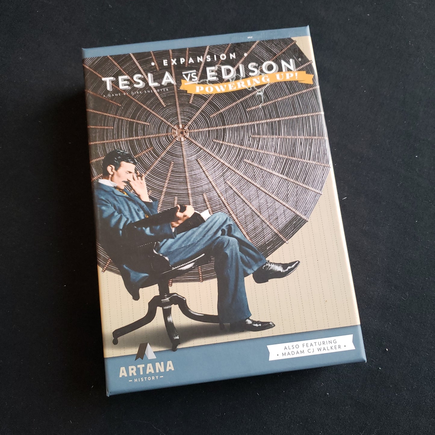 Image shows the front cover of the box of the Powering Up expansion for the board game Tesla vs Edison: War of the Currents