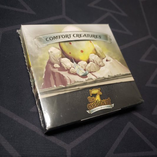 Image shows the front cover of the box of the Comfort Creatures expansion for the card game The 7th Continent