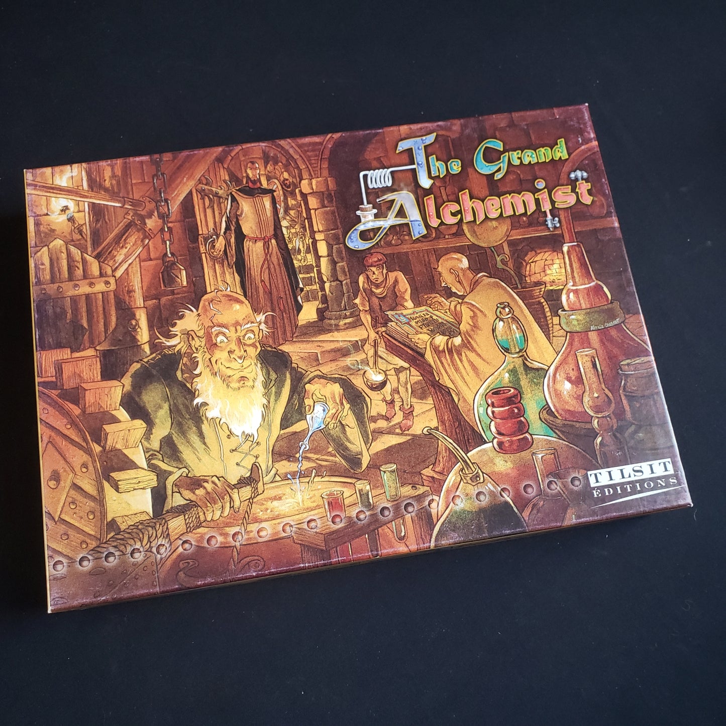 Image shows the front cover of the box of the Grand Alchemist board game