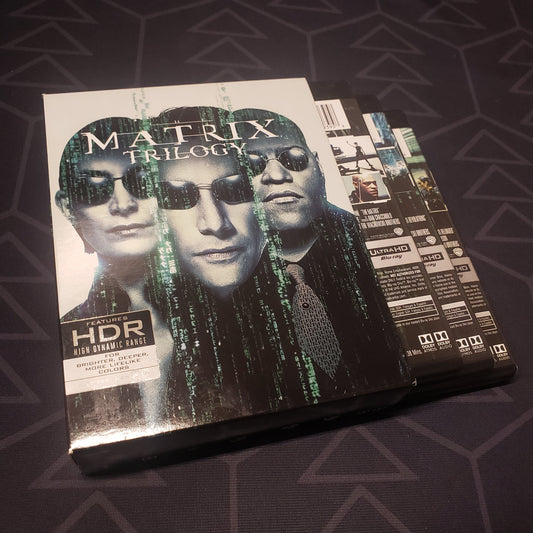 Image shows the outer box with three fanned-out disc cases for the movie set of The Matrix Trilogy on 4K Ultra HD