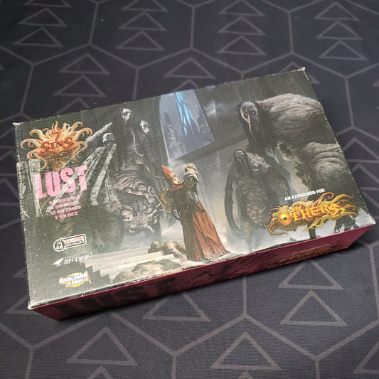 Image shows the front cover of the box of the Lust expansion for the board game The Others