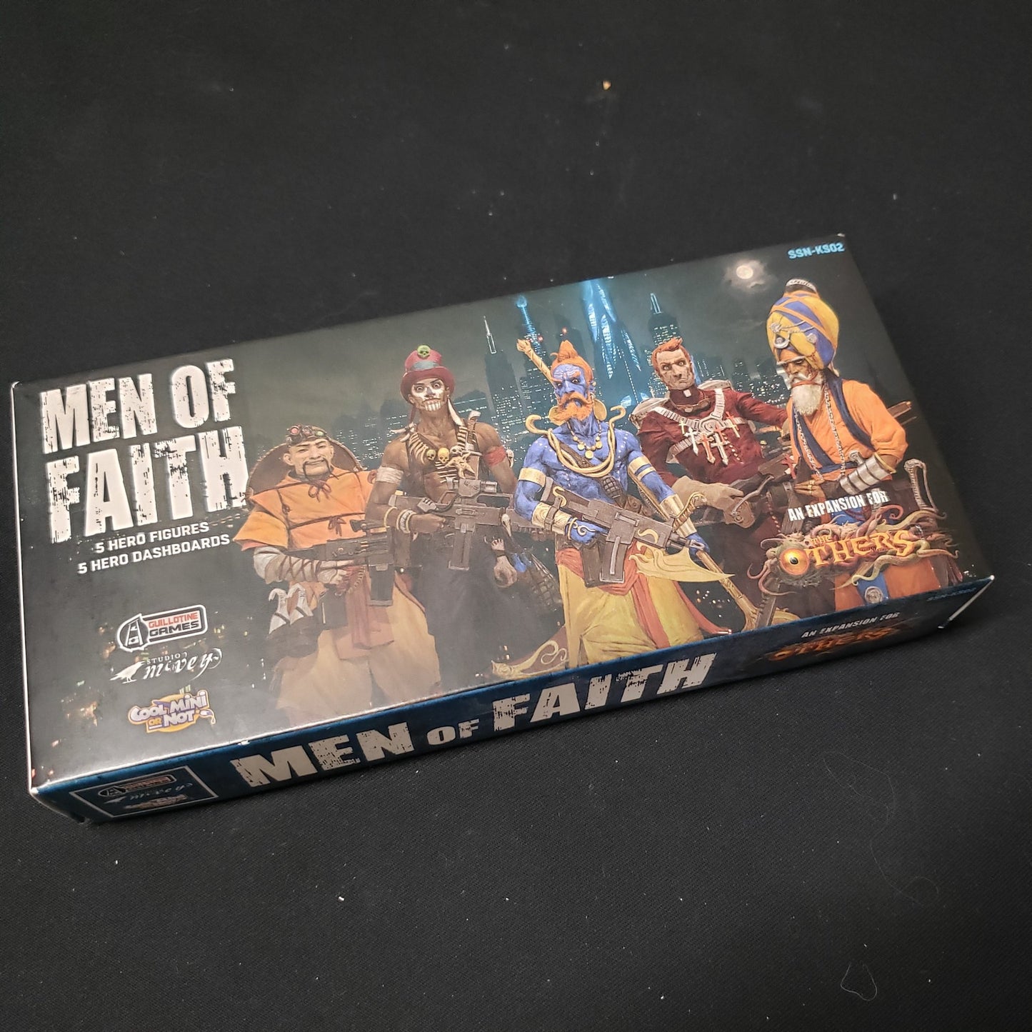 Image shows the front cover of the box of the Men of Faith expansion for the board game The Others