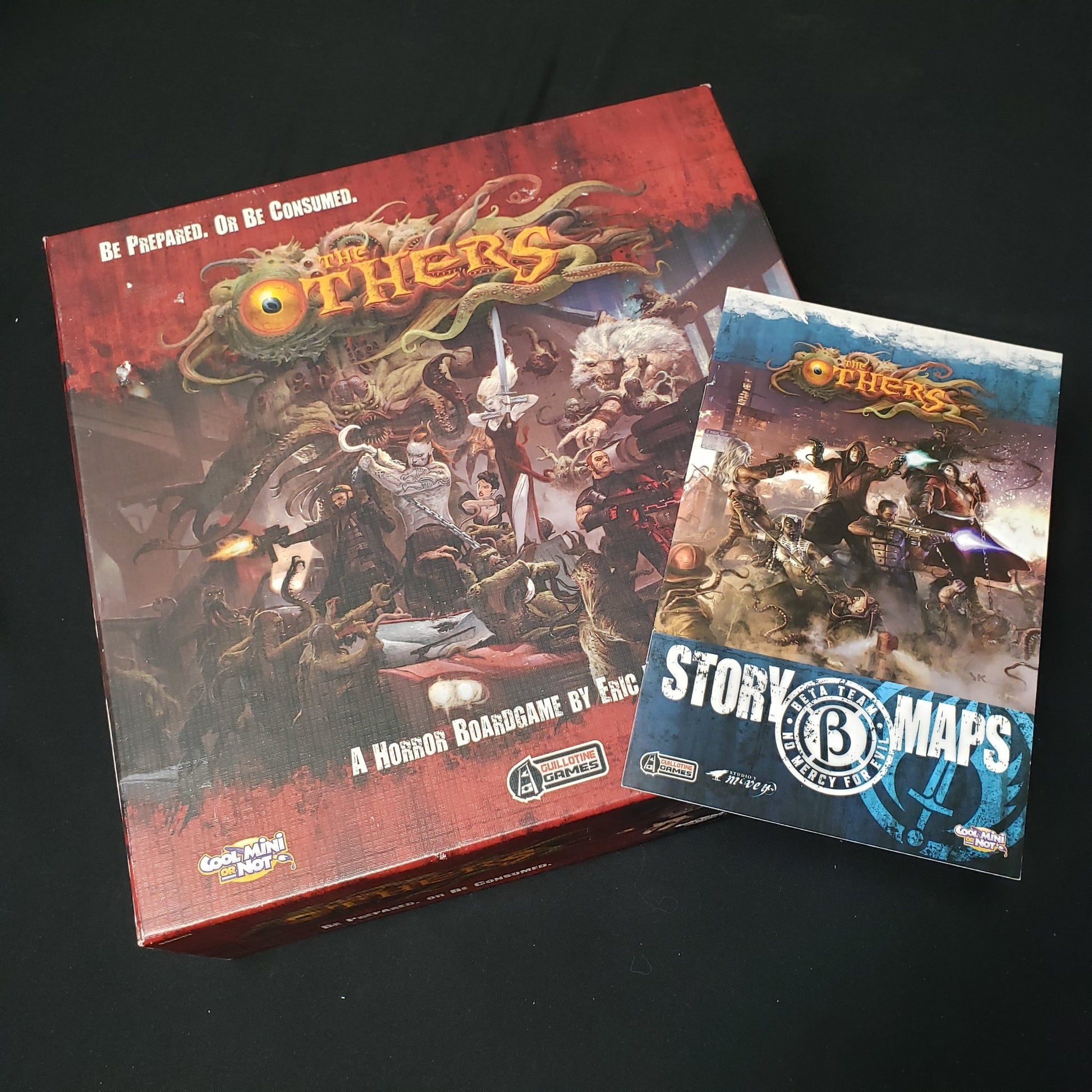 Image shows the front cover of the box of the Others board game, with the instructions for the Beta Team expansion sitting on top of it