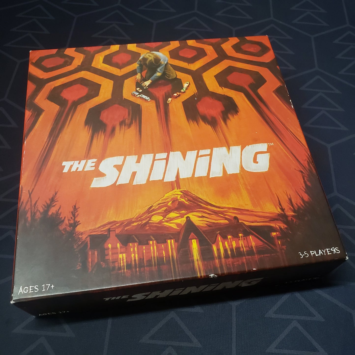 Image shows the front cover of the box for the board game The Shining