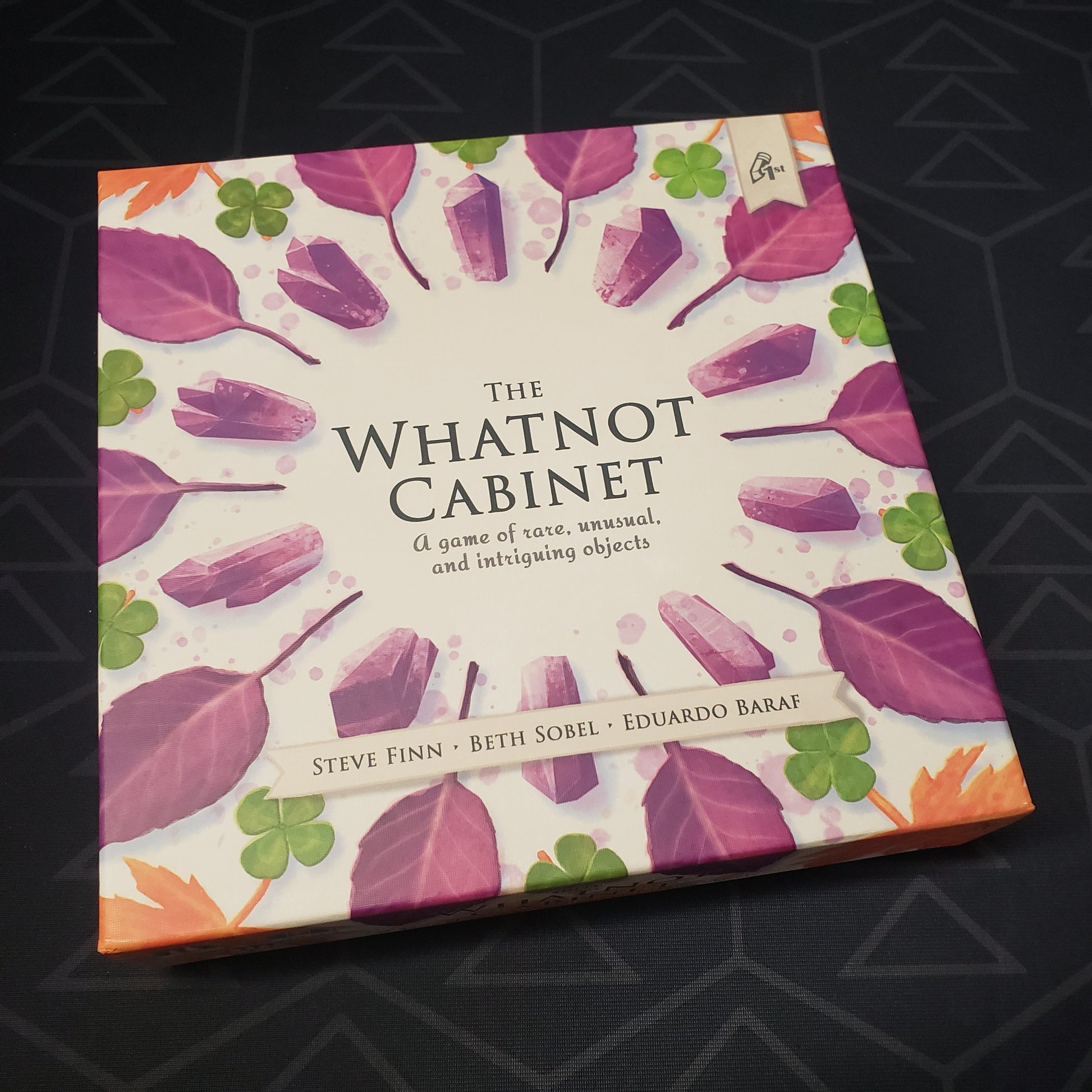 Image shows the front cover of the box for the board game The Whatnot Cabinet