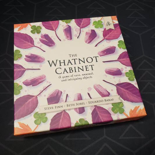 Image shows the front cover of the box for the board game The Whatnot Cabinet