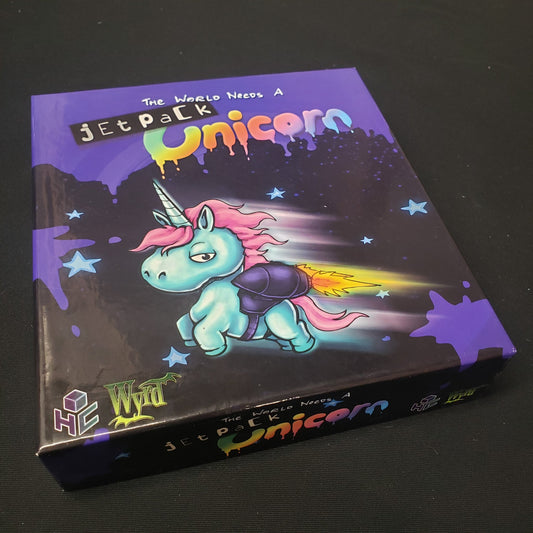 Image shows the front cover of the box of the The World Needs a Jetpack Unicorn party game