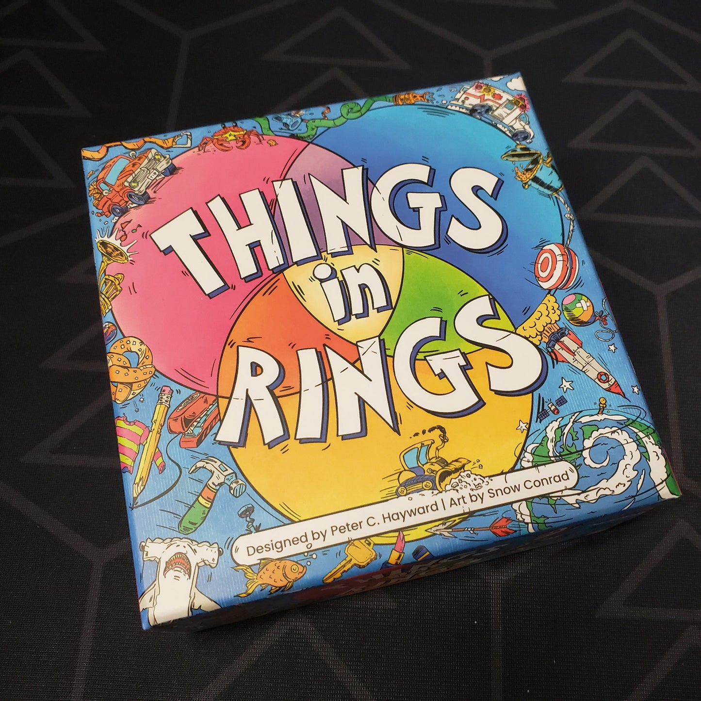 Image shows the front cover of the box of the Things in Rings card game