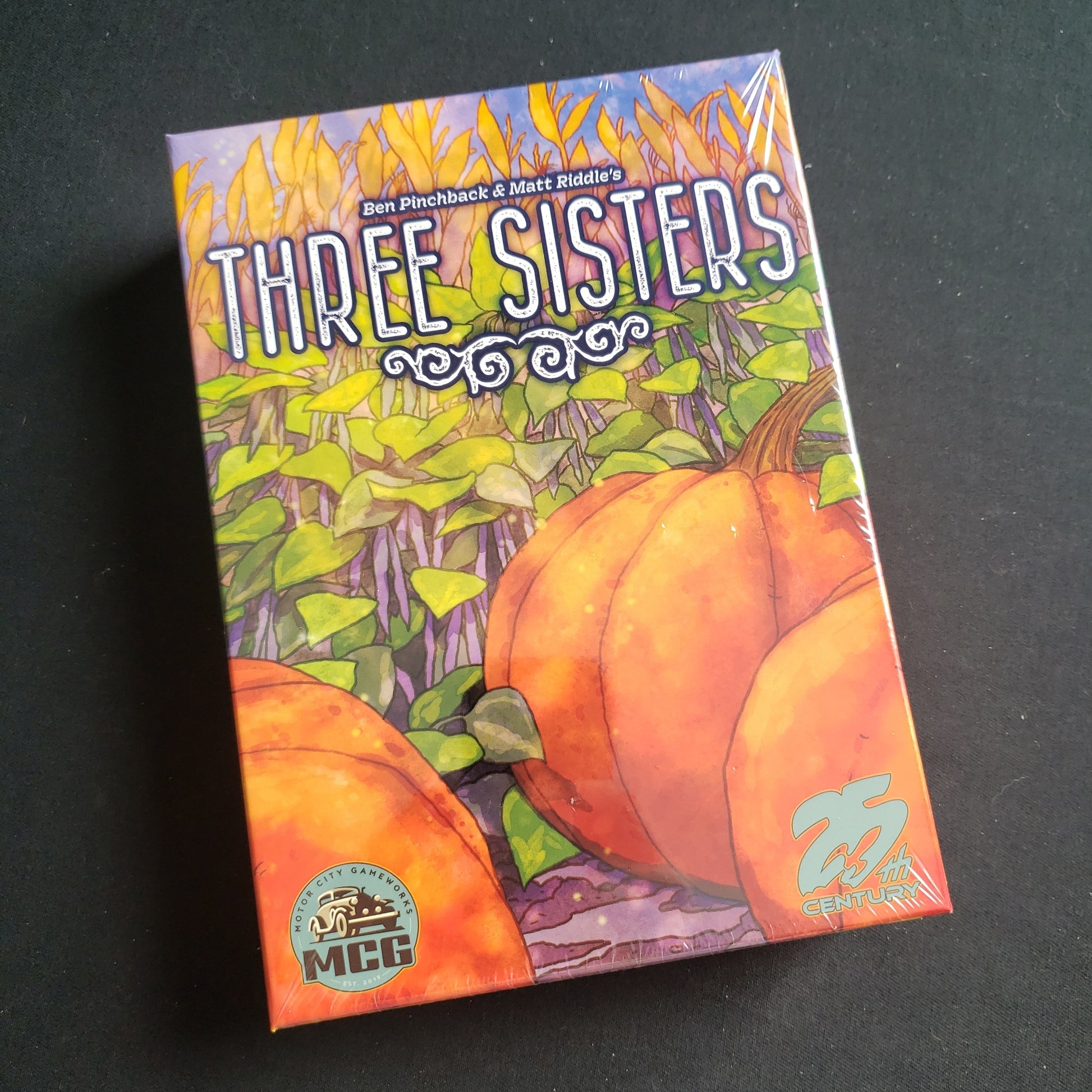 Image shows the front cover of the box of the Three Sisters board game