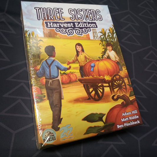 Image shows the front cover of the box for the board game Three Sisters: Harvest Edition