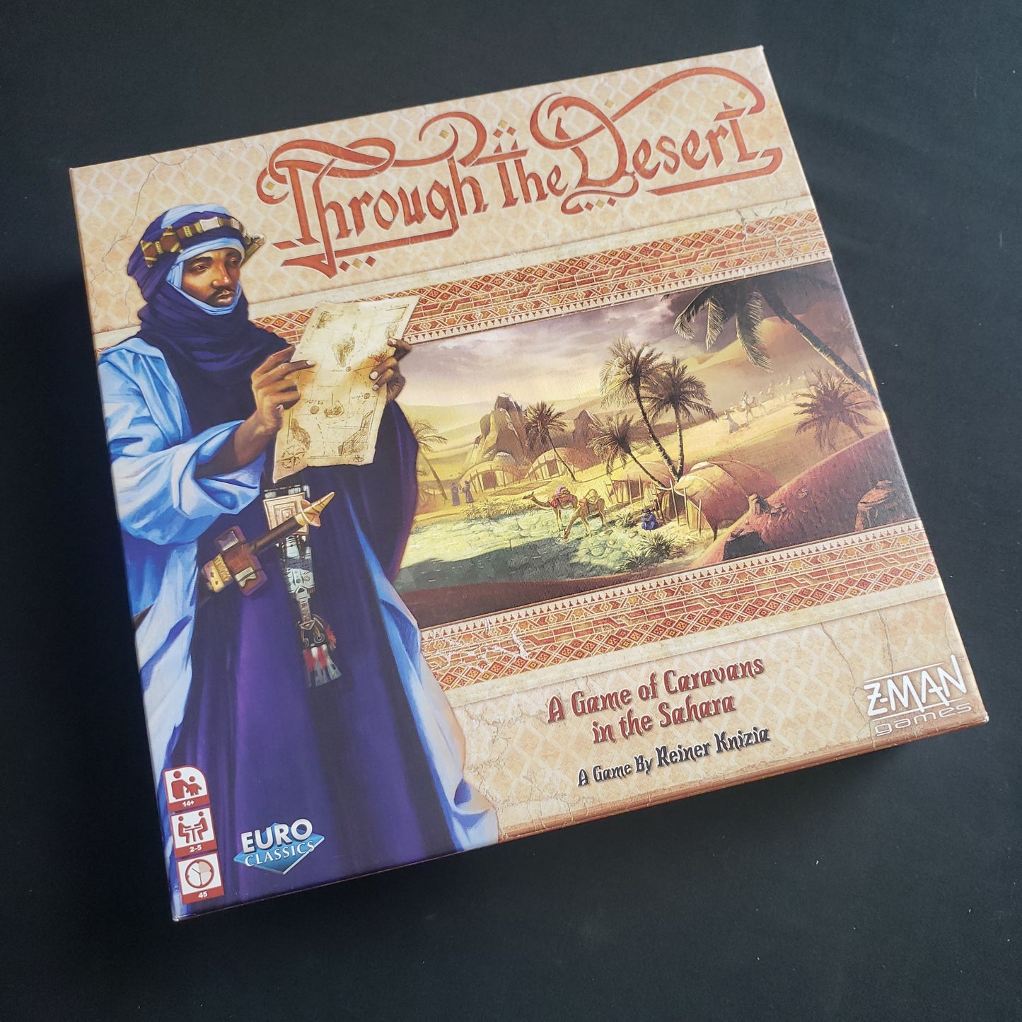 Image shows the front cover of the box of the Through the Desert board game