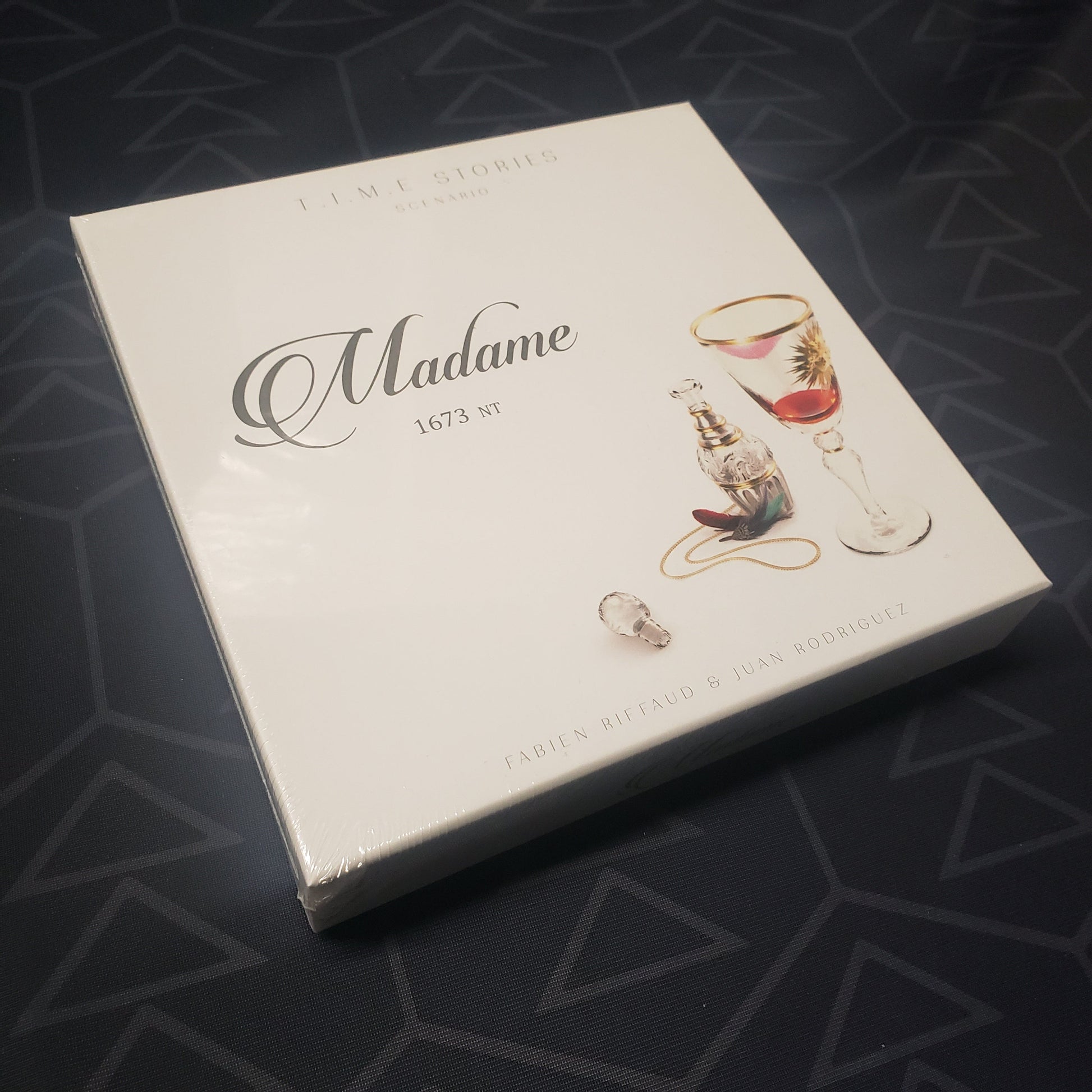 Image shows the front cover of the box of the Madame expansion for the board game T.I.M.E Stories