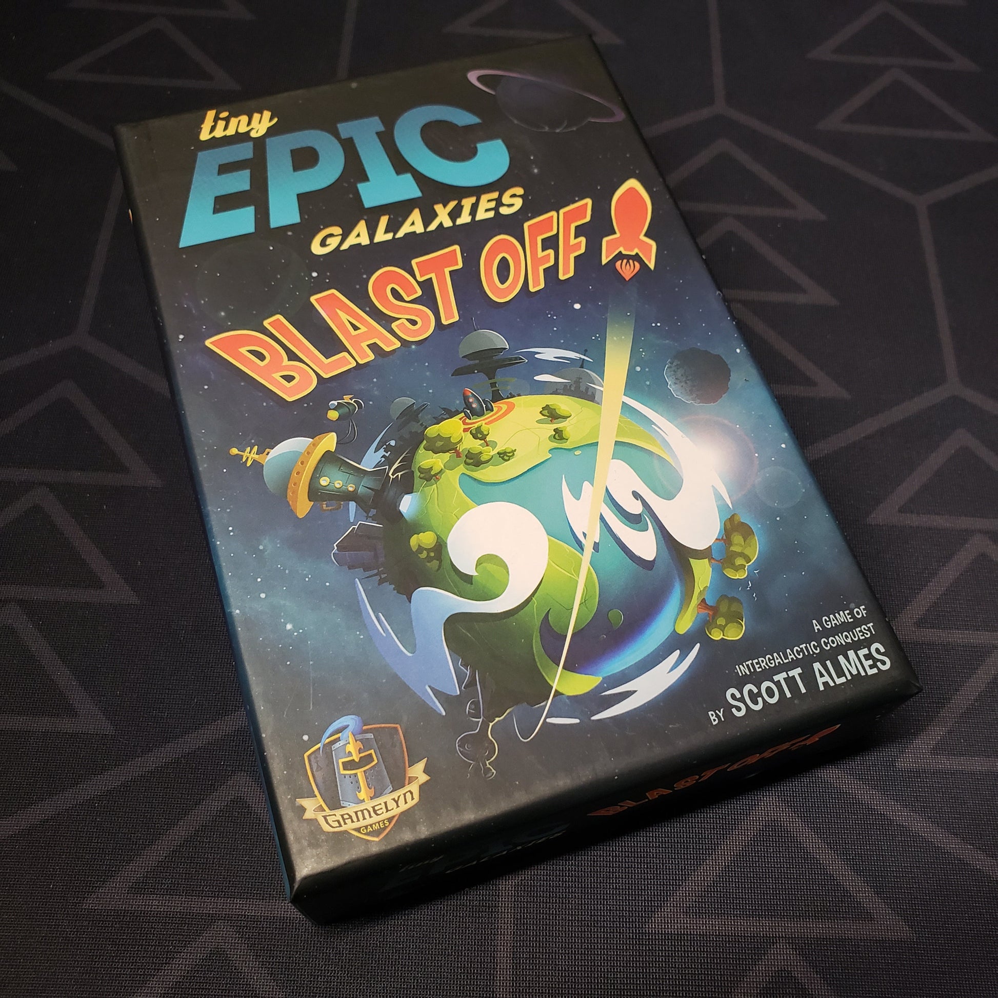 Image shows the front cover of the box for the Tiny Epic Galaxies BLAST OFF! board game