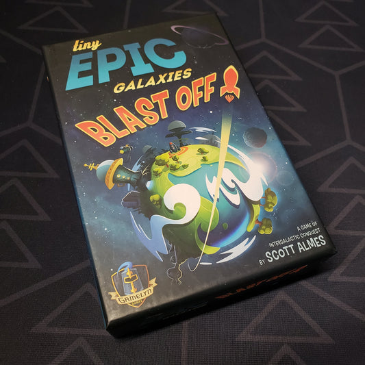 Image shows the front cover of the box for the Tiny Epic Galaxies BLAST OFF! board game