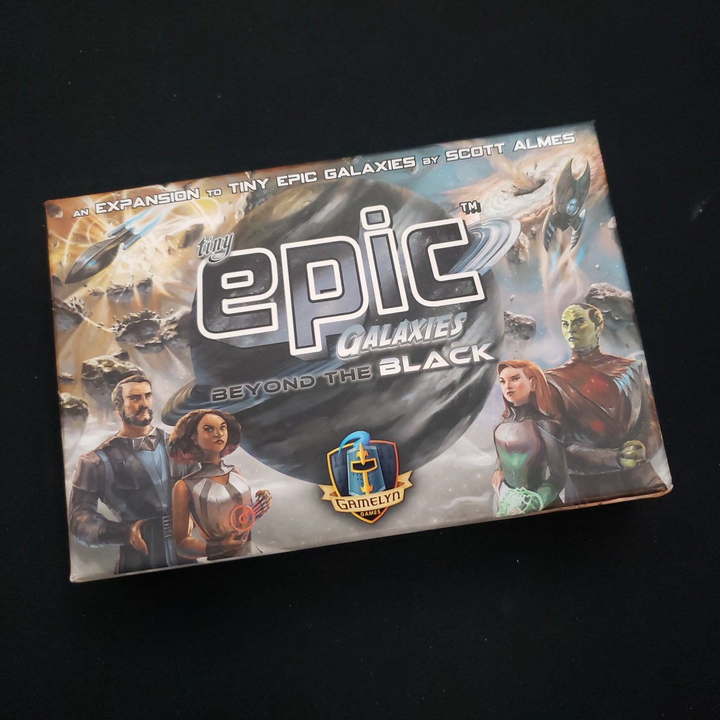 Image shows the front cover of the box of the Beyond the Black expansion for the board game Tiny Epic Galaxies