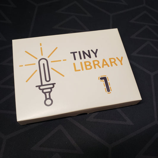 Image shows the front cover of the box of the Tiny Library Volume 1 set of micro RPGs
