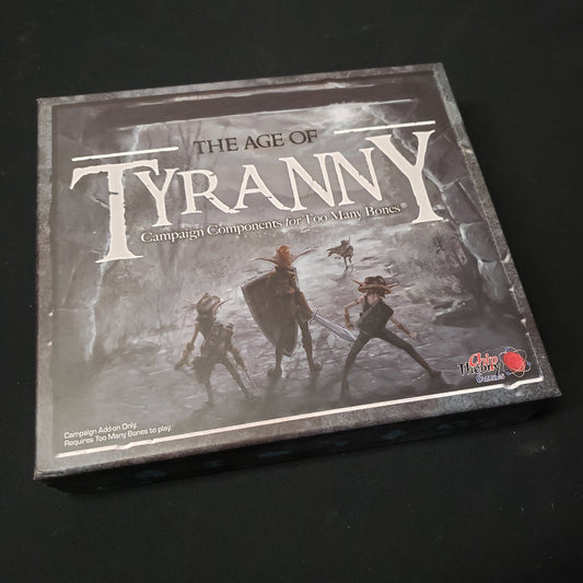 Image shows the front of the box for the Age of Tyranny expansion for the board game Too Many Bones