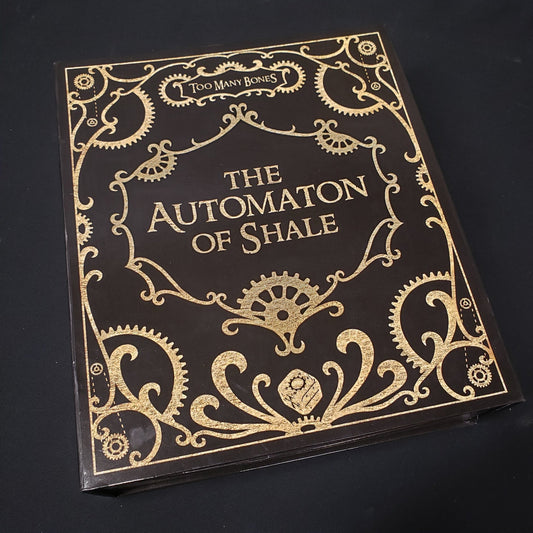 Image shows the front cover of the box of the Automaton of Shale expansion for the board game Too Many Bones