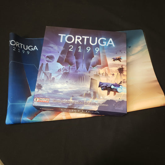 Image shows the front cover of the box of the Tortuga 2199 board game sitting on top of the playmat for the game