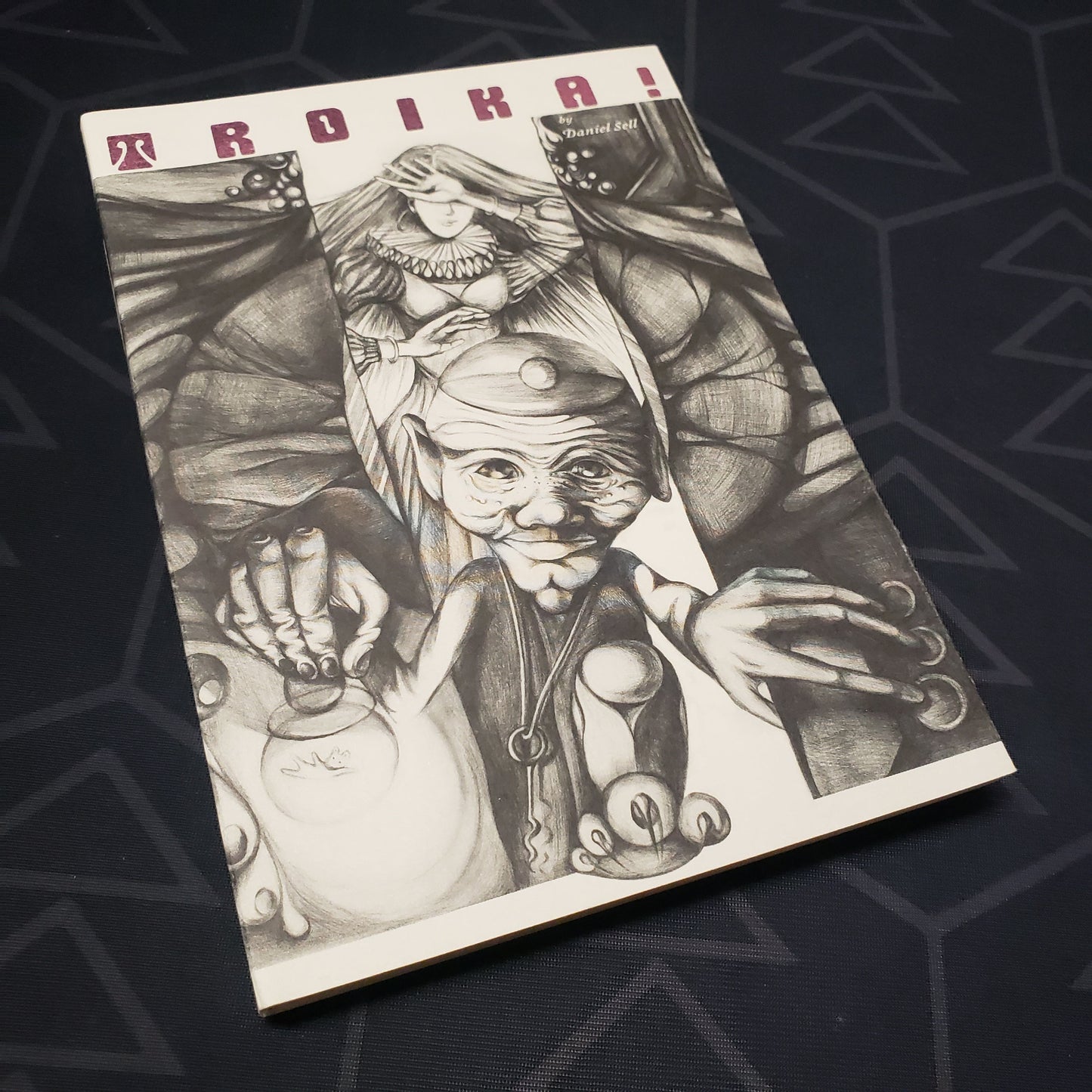Image shows the front cover of the Monochrome Softcover Numinous Edition core rulebook for the roleplaying game TROIKA!