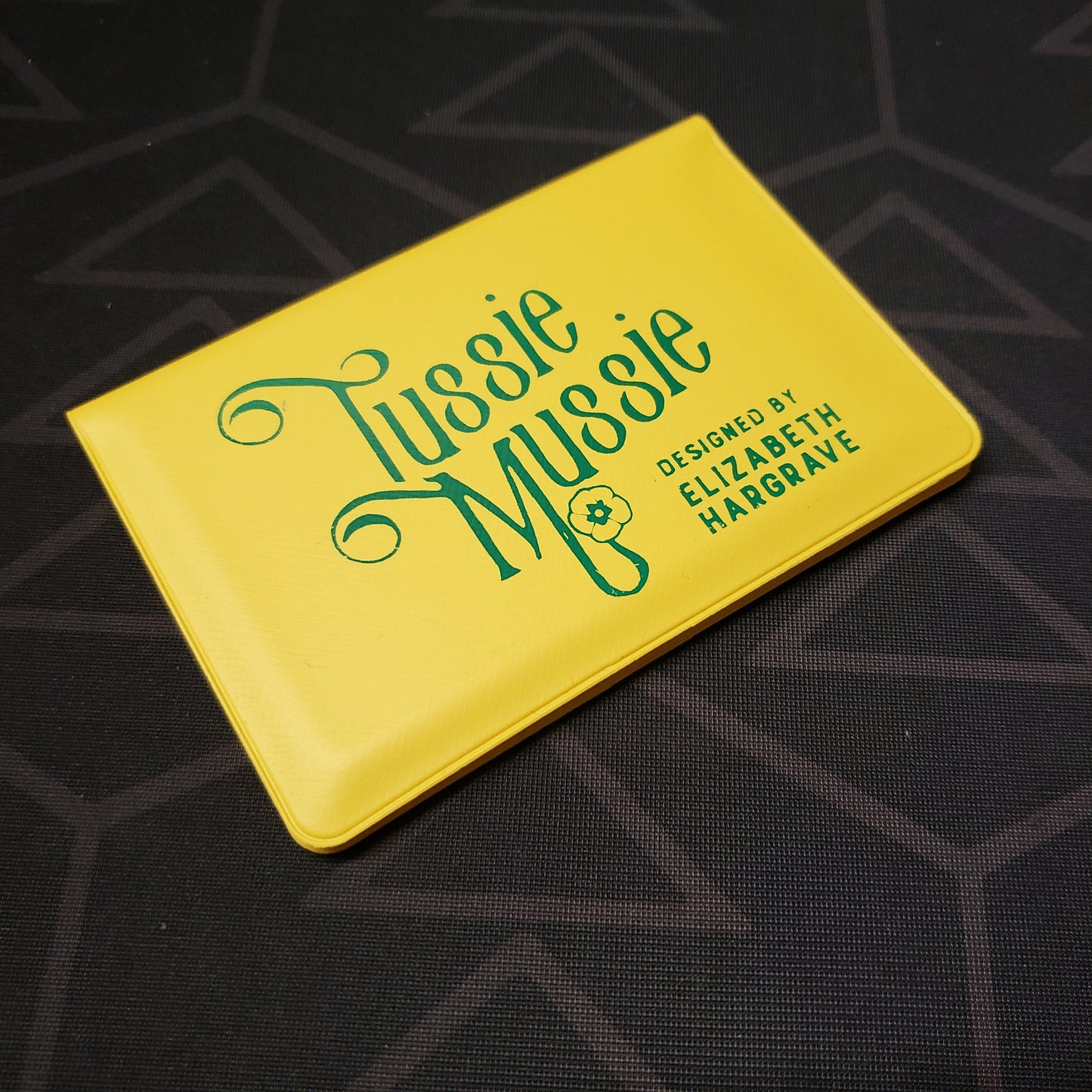 Image shows the front of the card wallet for the Tussie Mussie card game