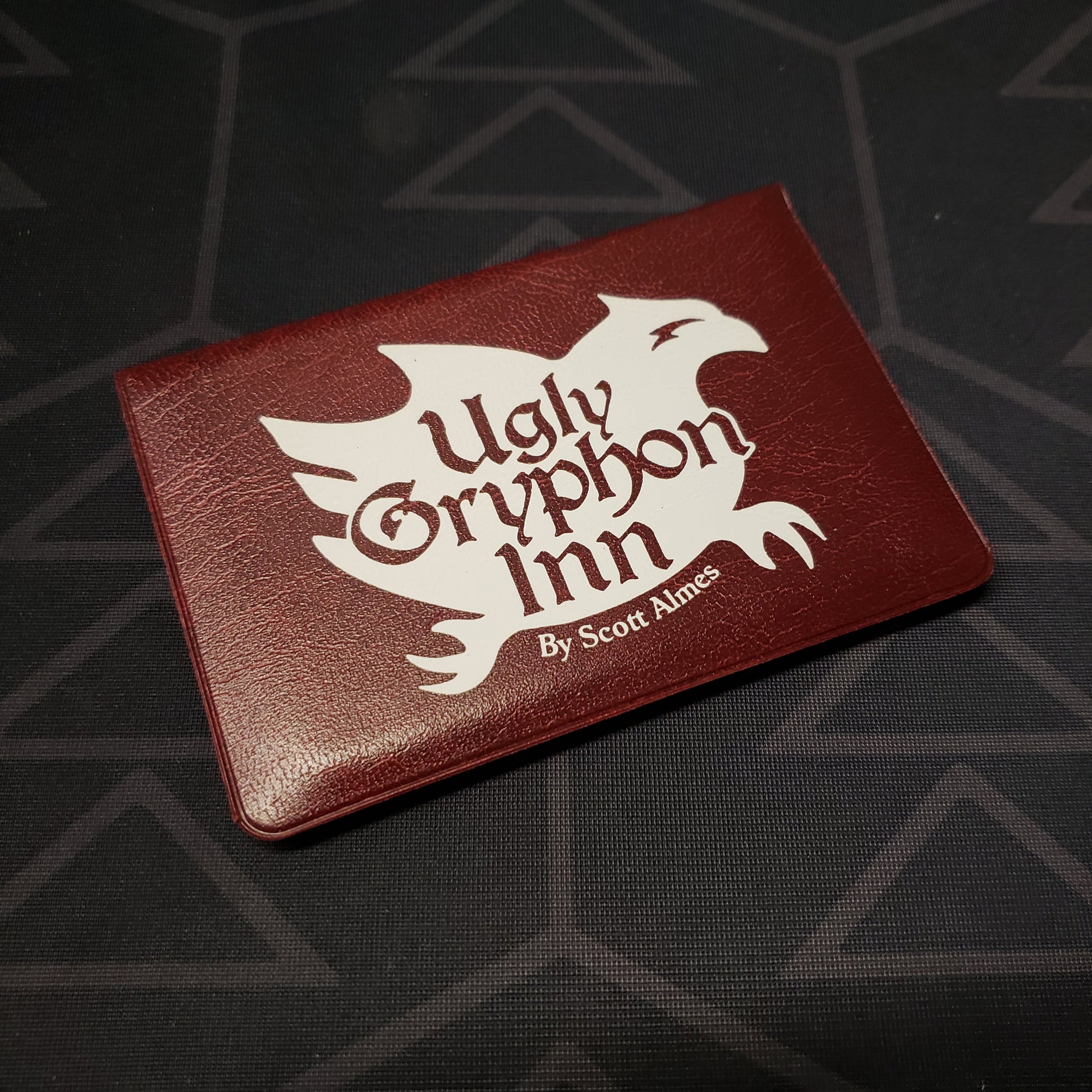 Image shows the front of the card wallet for the Ugly Gryphon Inn card game