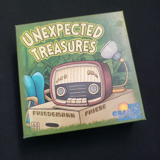 Image shows the front cover of the box of the Unexpected Treasures card game
