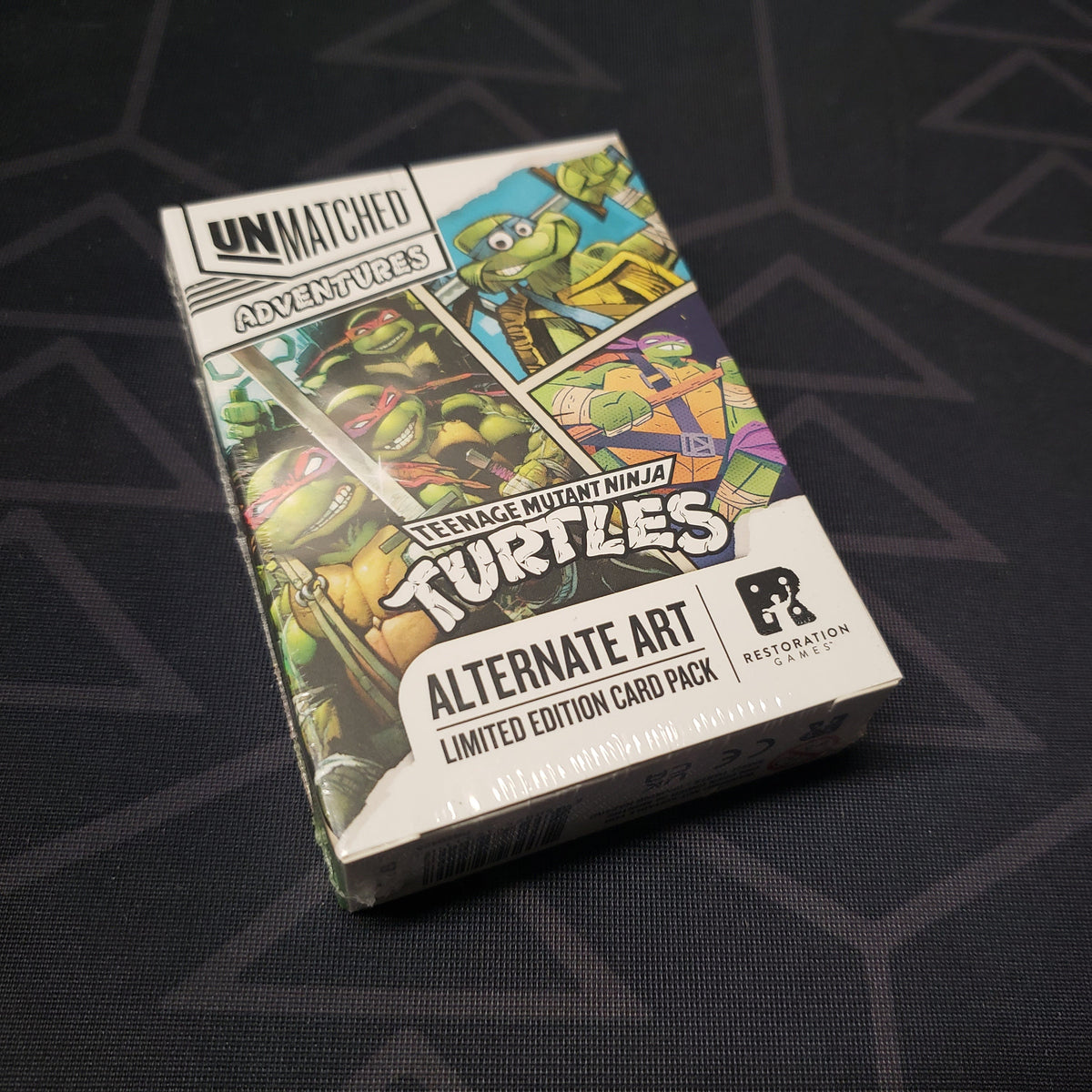 Image shows the front cover of the box of the Teenage Mutant Ninja Turtles: Alternate Art Limited Edition Card Pack for the board game Unmatched
