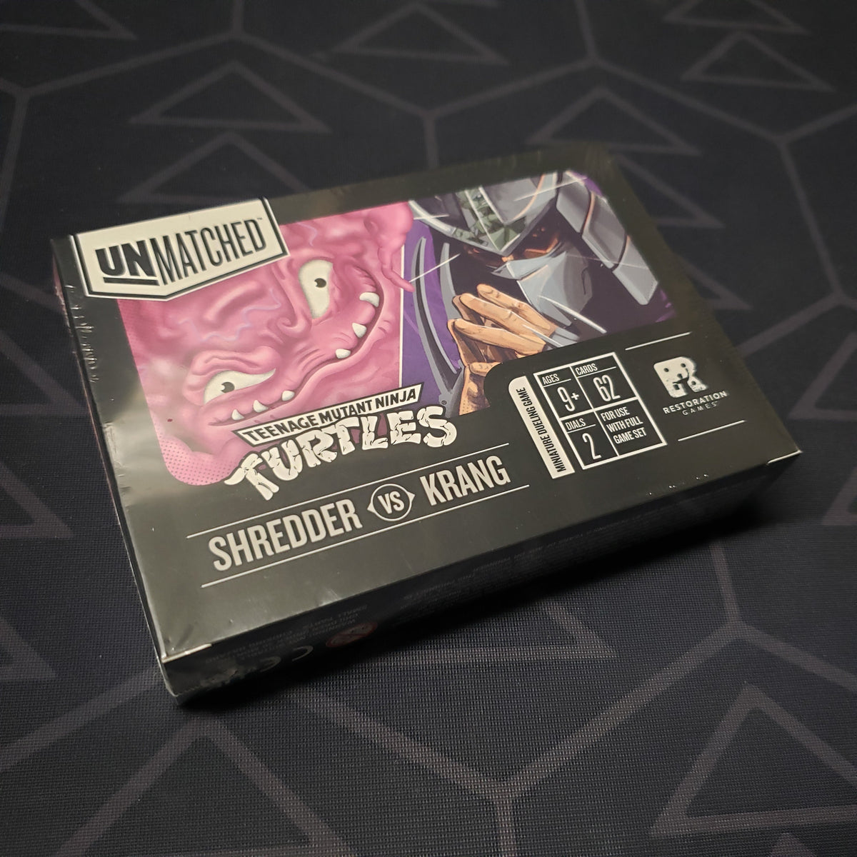 Image shows the front cover of the box of the Teenage Mutant Ninja Turtles: Shredder vs. Krang expansion for the board game Unmatched