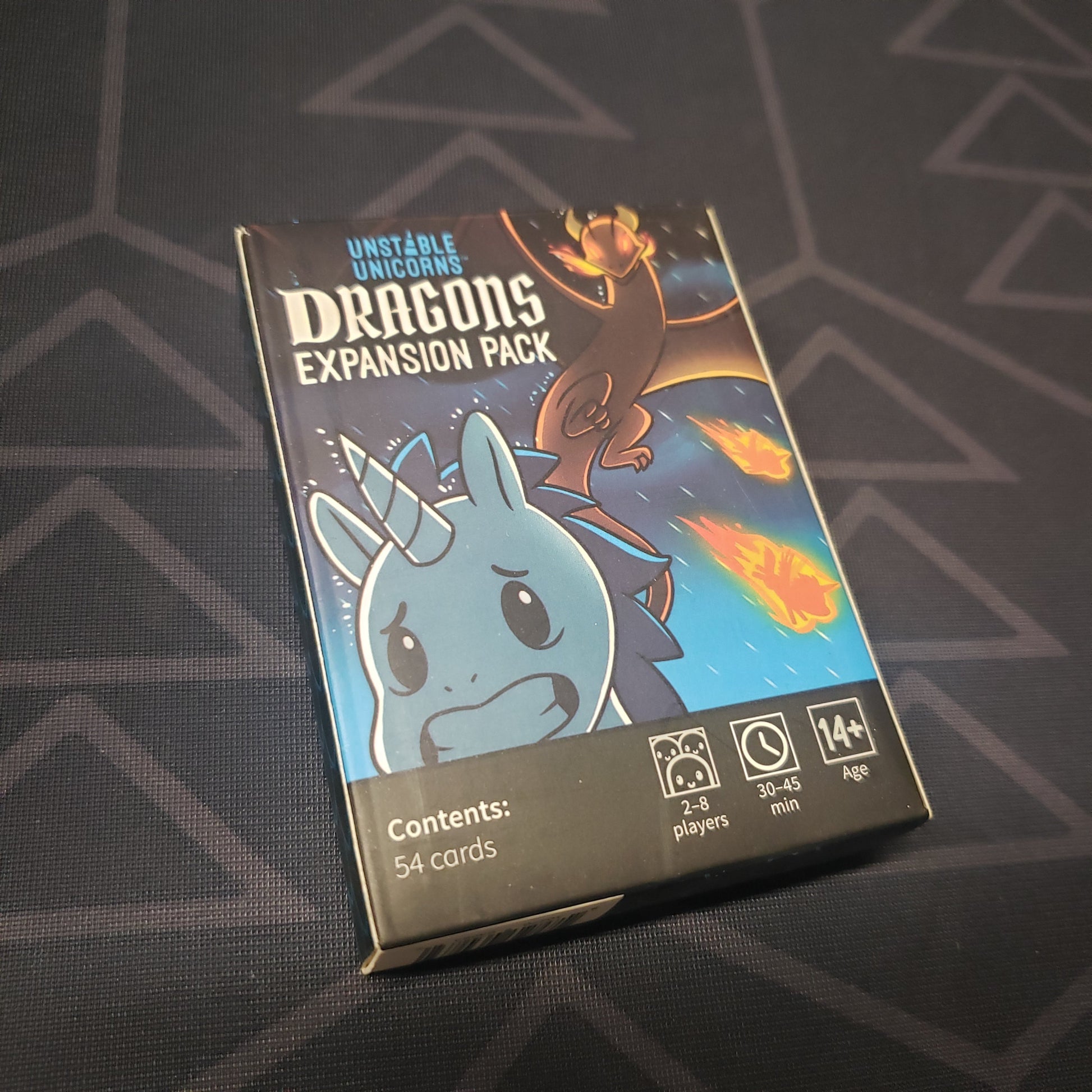 Image shows the front cover of the box of the Dragons expansion for the card game Unstable Unicorns