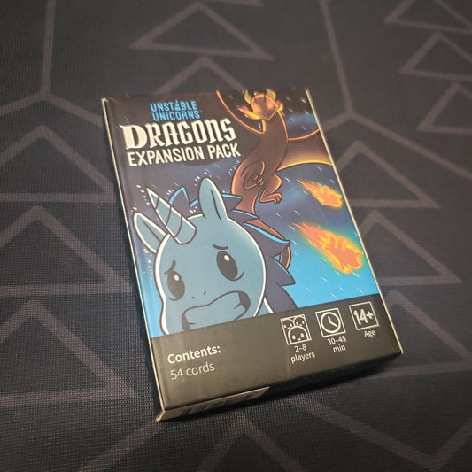 Image shows the front cover of the box of the Dragons expansion for the card game Unstable Unicorns